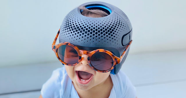 Baby trägt blauen Talee-Helm und hat eine Sonnenbrille auf